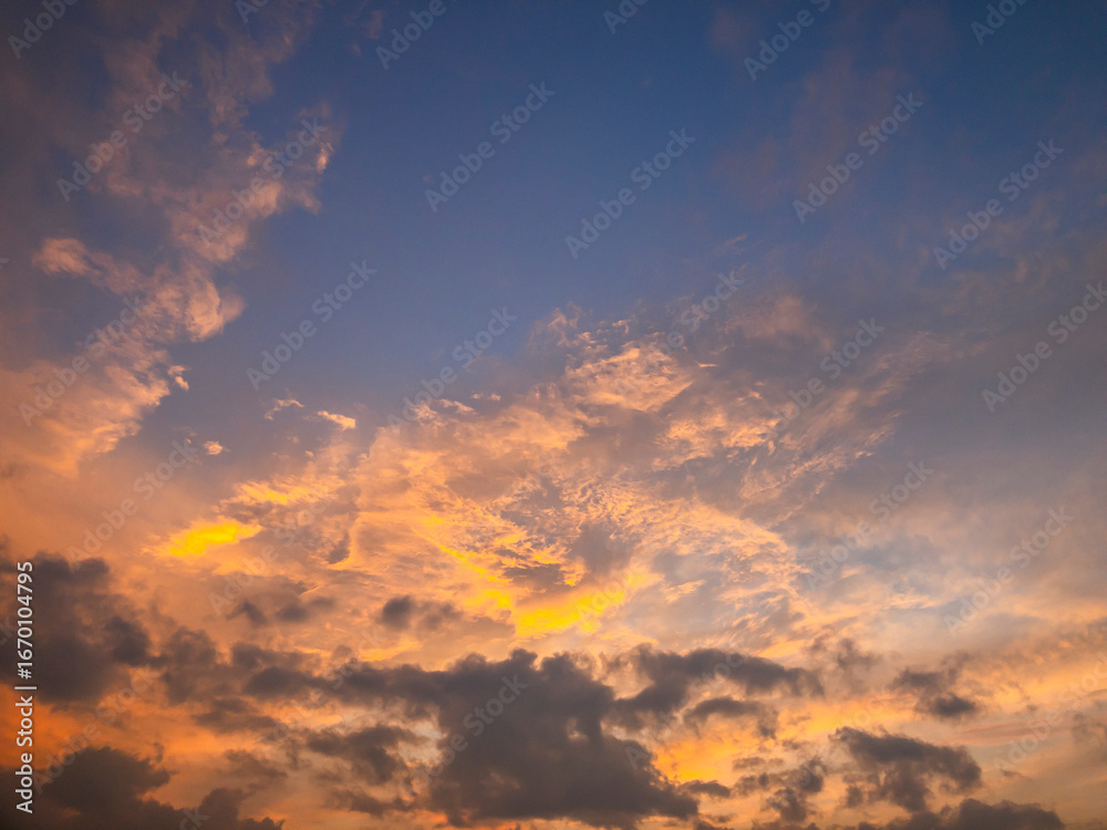 Obraz premium A breathtaking sky at sunset with glowing orange clouds fading into soft blue tones, captured in natural daylight, symbolizing beauty, peace, and awareness of environmental preservation.