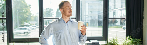Billede på lærred Handsome young businessman enjoys coffee while contemplating work in sunlit offi