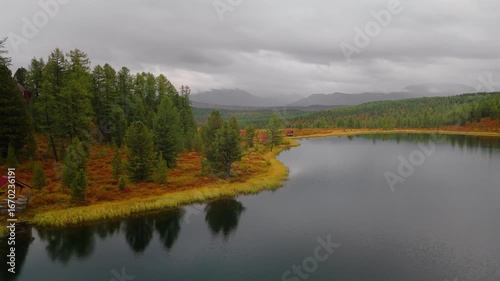 Aerial footage of Kidelu Lake, Altai Republic. Mountain lake with autumn forest and clear reflections, ideal for travel, outdoor adventure, and nature themes in stock footage.
