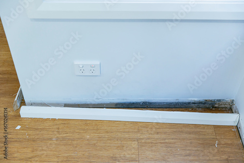 Baseboard removed along lower wall showing extensive mold damage and wall stains near power outlet in room undergoing renovation work