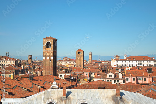 Venetian rooftops and medieval bell towers with Alps in background