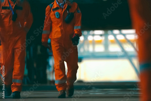 group of oil rig workers in orange overalls going to a work shif