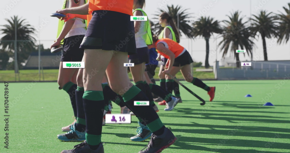 Obraz premium Sprinting teenage athletes practicing field hockey on coastal turf pitch, with floating data labels