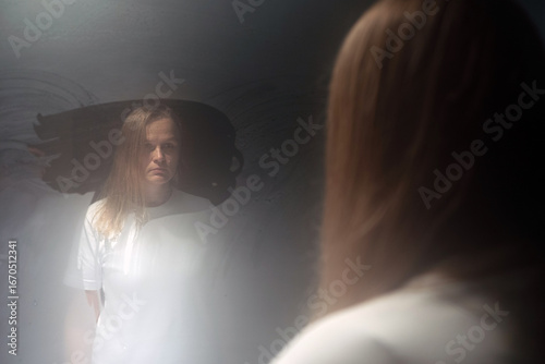 Fotografie Distressed patient gazing into a grimy mirror in a mental hospital, confronting