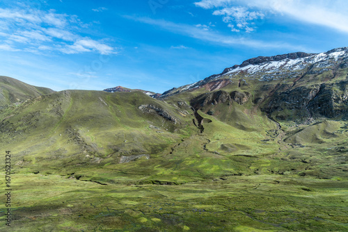 Lush green landscape of the Andes with snow capped peaks under a brilliant blue sky at Palcoyo Trek in Peru
