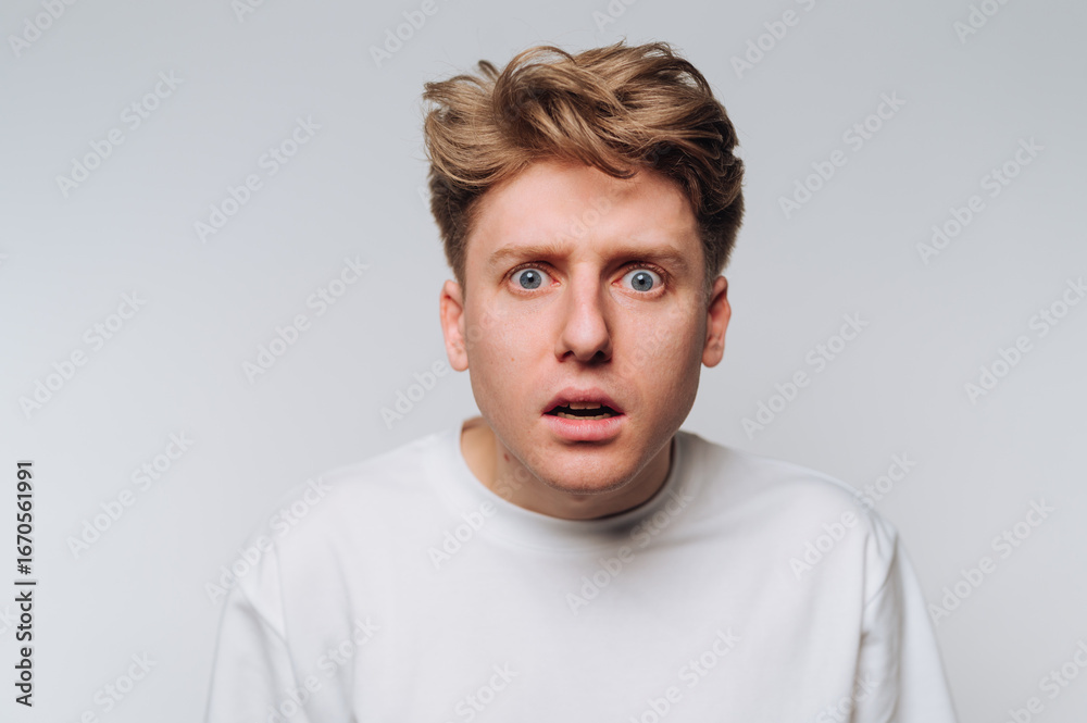 Fototapeta premium Man shows surprised expression against plain background during indoor session