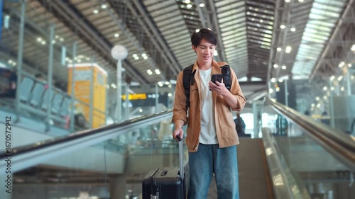 Happy asian man with backpack checking flight in phone on escalator in airport terminal, People concentrating typing digital device for travel in transportation, Concept of travel