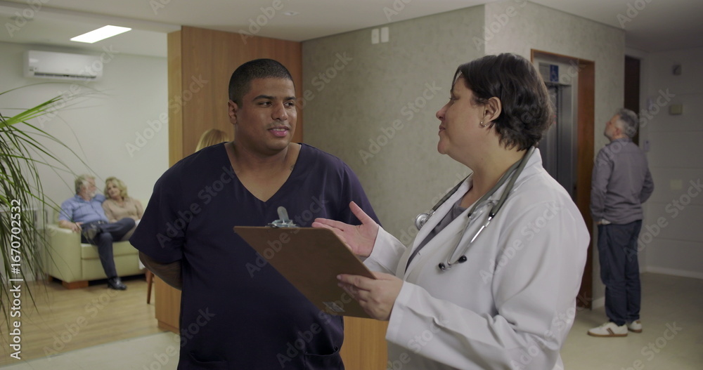 Fototapeta premium Doctor and nurse reviewing patient chart together in hospital hallway with engaged focus and medical teamwork during daily round