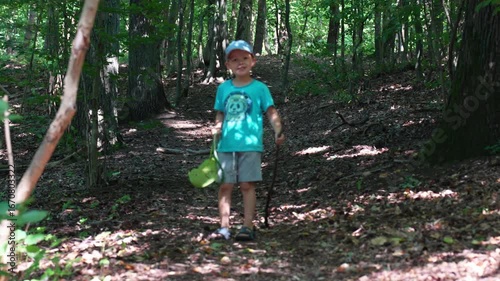 Young child running through dense forest trail in slow motion between tall trees. Concept of childhood adventure, nature exploration and outdoor freedom. High quality 4k footage