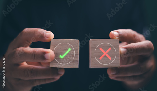 Business decision-making concept. Businessman hands holding wooden blocks featuring green check mark and red cross symbols. Representing correct and wrong choices, risk management and judgment.