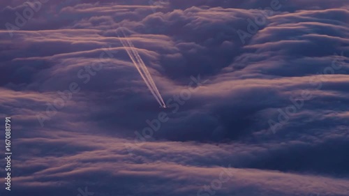 An airplane flying above the clouds at sunset, the glowing contrails and dramatic cloud textures create a stunning aerial view.