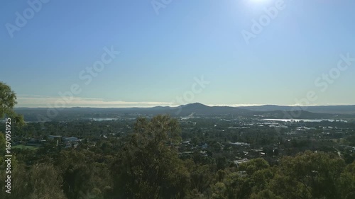 Rising above the tree canopy to reveal ACT Canberra Australia in the morning sun.