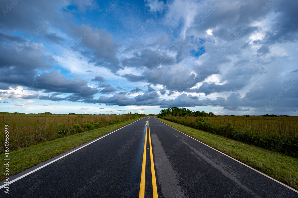 Fototapeta premium Bright summer cloudscape over Main Park Road in Everglades National Park, Florida.