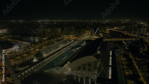 Night aerial drone footage over Valencia city park with futuristic cultural buildings and river view. Spain.