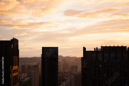 City skyline at sunset with buildings silhouetted against an orange sky, high...