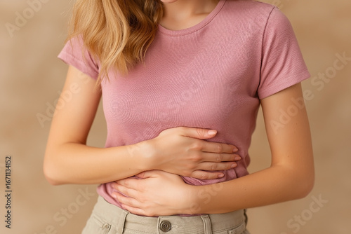 Wallpaper Mural Woman is wearing a pink shirt and holding her stomach. She is in pain. Concept of discomfort and distress Torontodigital.ca