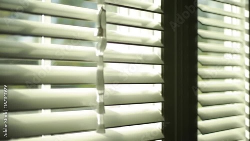 Close up of white window shutters with sunlight filtering through the slats indoors at daytime