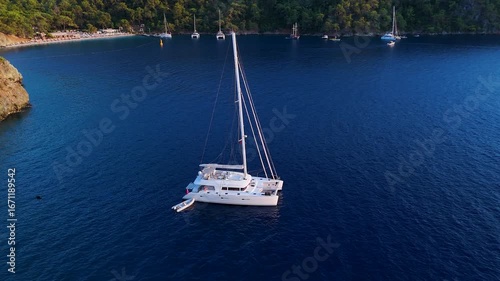 A magnificent 4K aerial shot of a white catamaran sailing boat anchored in a pristine turquoise cove a beautiful and serene image of a luxury travel and yachting lifestyle vacation