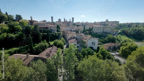 A flying shot over Bergamo alta ancient roofs. From green trees discovering the ancient town