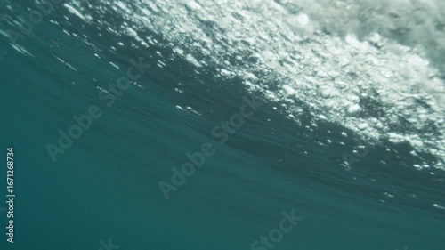 Slow motion of underside of ocean wave, smooth textures and filtered light from below