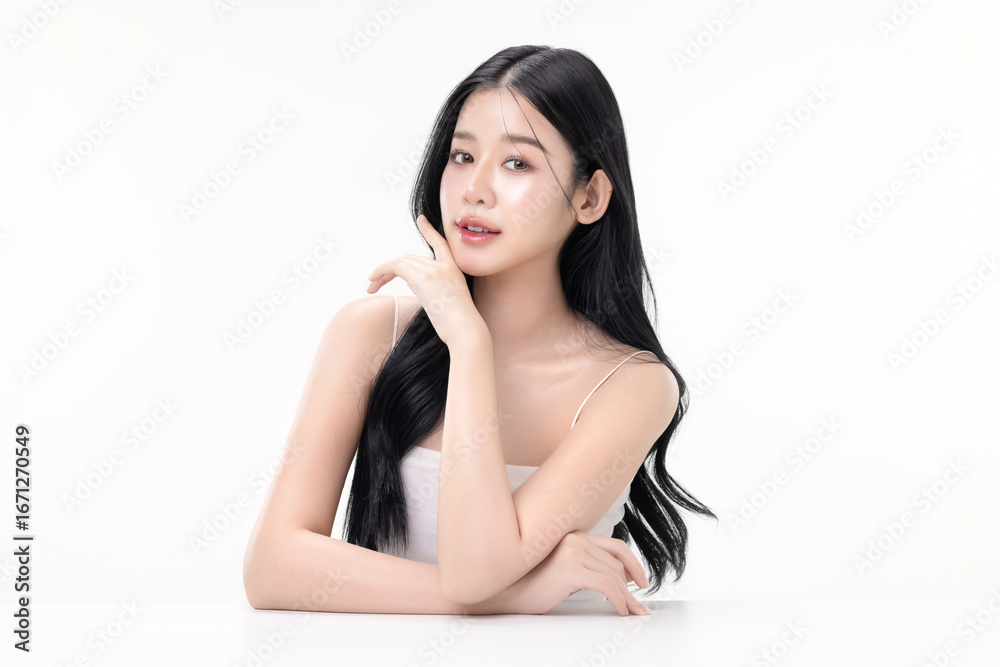A beautiful Asian woman with long black wavy hair posing gracefully with a soft smile isolated on white background, studio beauty portrait for skincare, cosmetics, commercial ads. A beautiful Asian woman with long black wavy hair posing gracefully with a soft smile isolated on white background, studio beauty portrait for skincare, cosmetics, commercial ads.