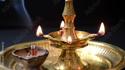 A traditional brass lamp and incense burner illuminate a dark backdrop with gentle smoke