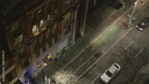 Cars and People moving along a busy street at night.