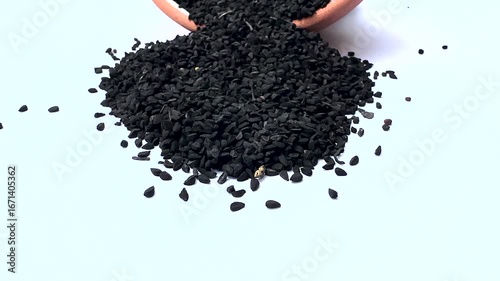 Black Cumin Spilled from Terracotta Bowl on White background