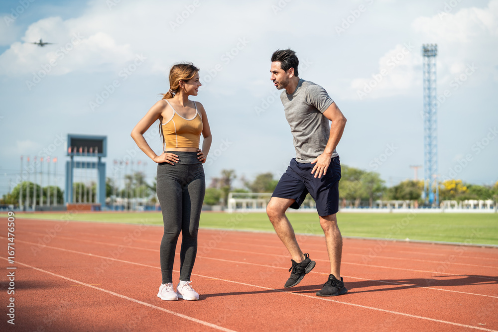 Fototapeta premium Diverse young man and woman athletes exercising together at stadium. 