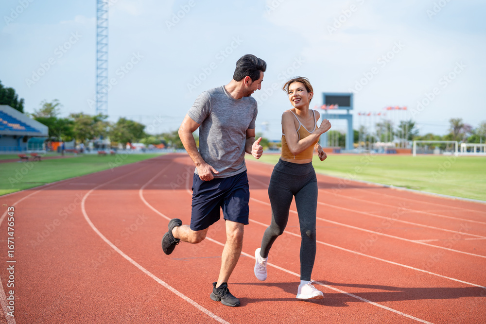 Fototapeta premium Diverse young man and woman running exercising together at stadium.