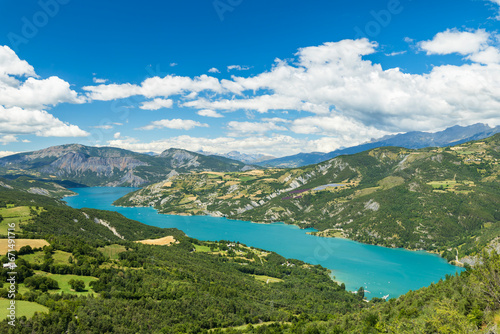 Serre Poncon Lake Embracing Green Valley under Cloudy Sky in French Alps