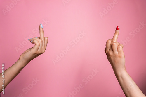 Tableau sur toile Young woman's hands giving each other the middle finger on a pink background