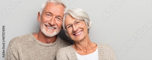 Portrait of smiling elderly couple in casual clothes on plain background with space to right