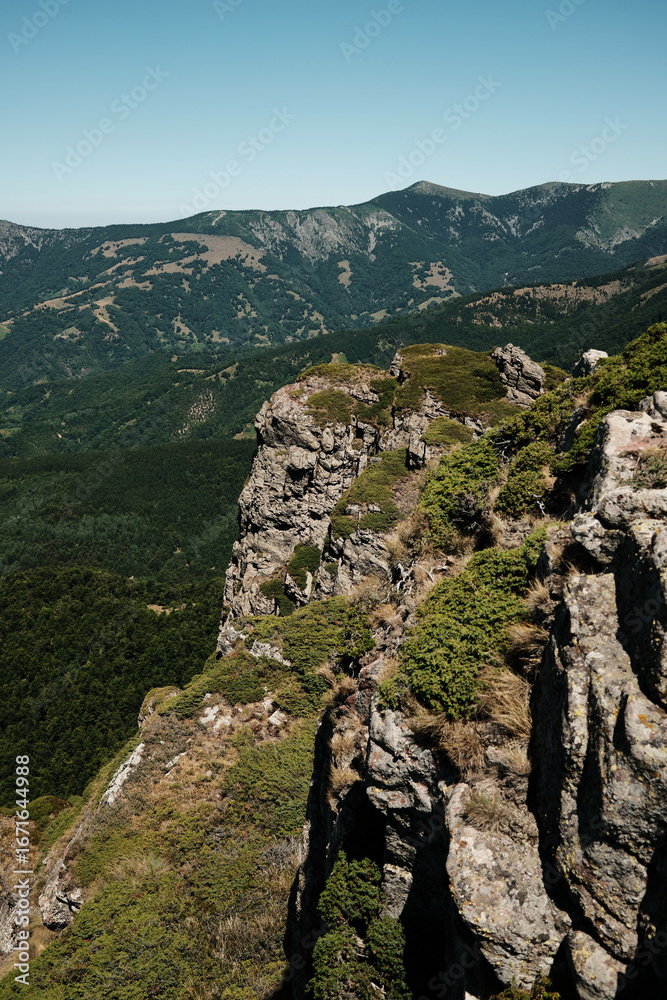 Obraz premium Rocky cliffs and green slopes of Stara Planina with mountain ridges in the distance. Babin Zub mount in summer season. Serbia country