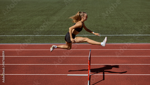 Female hurdler mid-air jumping hurdle on track. Concept of overcoming barriers, strength in motion, determination, resilience, and pushing limits in athletics.