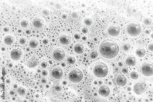 Close-up of white soapy foam with various-sized bubbles, creating an abstract texture. Light reflects on the bubbles