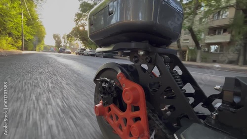 Movement on an electric scooter through the city. Camera is mounted on the scooter and directed at the rear wheel, showing motion, asphalt road, and modern urban transport concept with eco mobility.