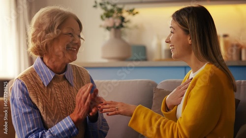 Young woman showing engagement ring to her happy senior mother at home