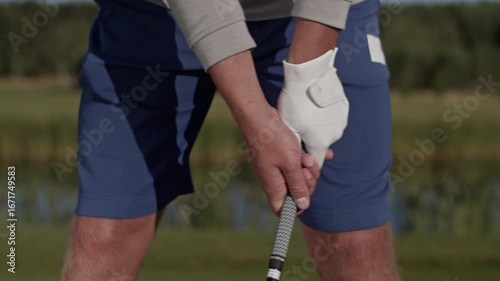 Golfer with glove adjusts grip on golf club preparing for shot