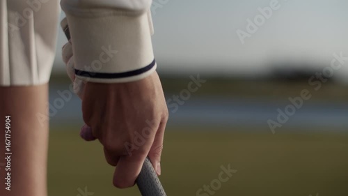 Woman golfer adjusts grip on golf club standing on country course