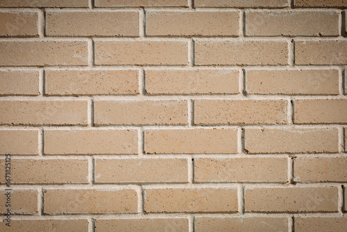 A smooth brick wall made of light clinker brick. The bricks are laid in a checkerboard pattern, the seams between them are neat. The wall surface is smooth, without defects.