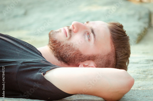 Foto Young man relaxes on a rocky surface in natural light