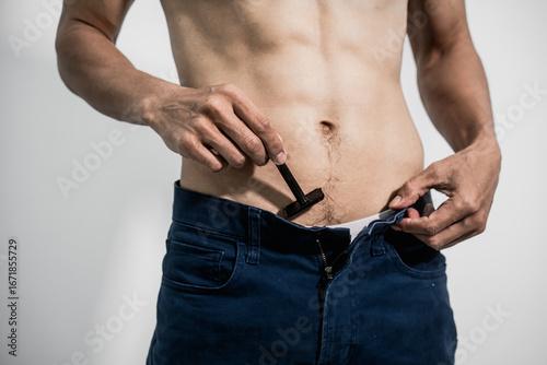 Canvastavla Asian man practices intimate grooming with precision, shaving pubic hair in the groin area using professional tools, achieving smooth skin, hygiene, and confidence and masculine body care
