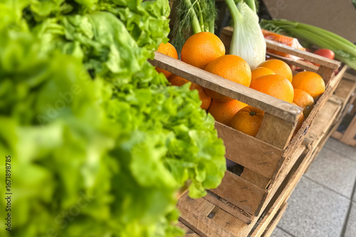 Photos greengrocer with fresh organic oranges, grapefruit,  and lettuce in wooden baske
