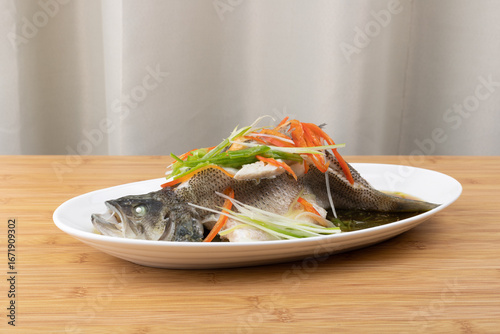 Steamed sea bass in a white porcelain plate