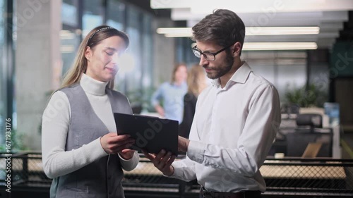 A man and a woman are talking in a room with a white background