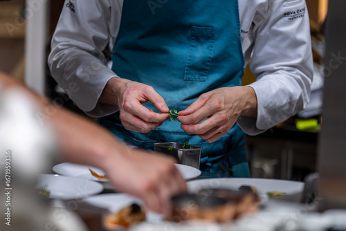 Foto Main d’un chef étoilé en pleine préparation culinaire, dressant un plat gastronomique avec précision