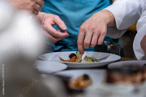 Bild auf Leinwand Main d’un chef étoilé en pleine préparation culinaire, dressant un plat gastronomique avec précision