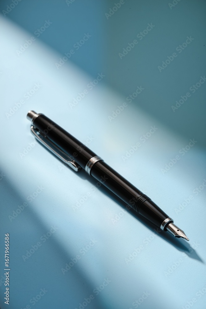 Elegant Black Fountain Pen Resting on Light Blue Surface Elegant Black Fountain Pen Resting on Light Blue Surface