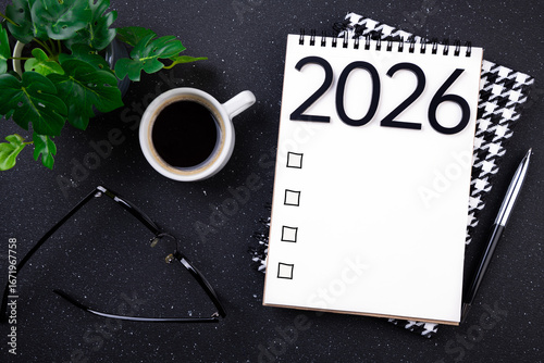New year resolutions 2026 on desk. 2026 goals list with notebook, coffee cup, plant on black table. Resolutions, plan, goals, action, checklist, idea concept. New Year 2026 resolutions, copy space